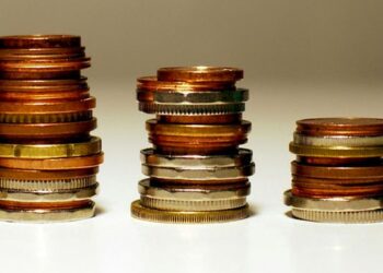 Gestapelte Münzen in unterschiedlichen Höhen symbolisieren finanzielle Schwankungen und wirtschaftliche Trends.