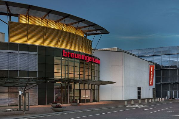 Moderne Einzelhandelsfläche mit großflächiger Glasfassade und rotem Schriftzug bei Dämmerung