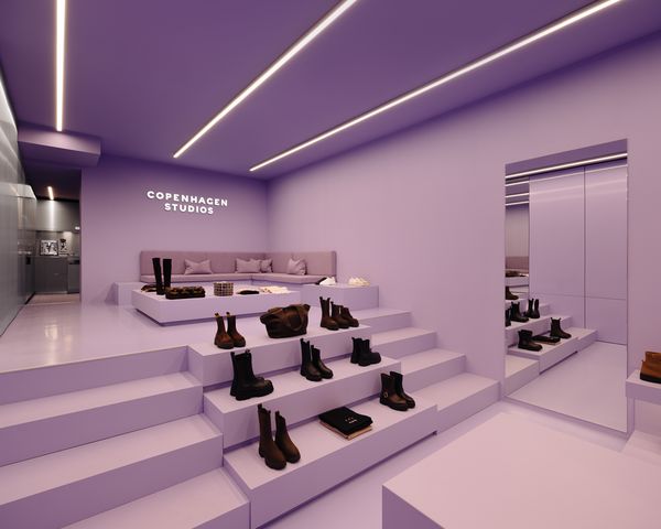 Moderner Retail-Space in Violett mit LED-Deckenleuchten, Schuhausstellung auf gestuften Podesten und großem Spiegel an der Wand.