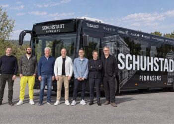 Gruppenfoto von etwa zehn Personen vor einem schwarzen Bus mit Schuhstadt-Schriftzug bei Tageslicht.
