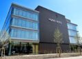 Modernes Bürogebäude der Hugo Boss mit dunkler Fassade und großflächigen Fenstern, umgeben von Bäumen und Grünanlagen.