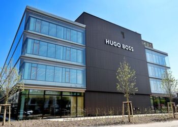 Modernes Bürogebäude der Hugo Boss mit dunkler Fassade und großflächigen Fenstern, umgeben von Bäumen und Grünanlagen.