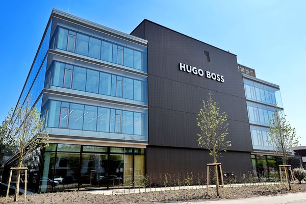 Modernes Bürogebäude der Hugo Boss mit dunkler Fassade und großflächigen Fenstern, umgeben von Bäumen und Grünanlagen.