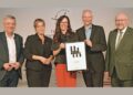 Fünf Personen in Business-Kleidung halten ein Zertifikat und eine Urkunde in die Kamera, anlässlich einer Preisverleihung für Ehrenamt.