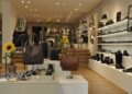 Modernes Schuhgeschäft mit Ausstellungsfläche, Regalen an den Wänden mit Schuhen und Accessoires, Verkaufstischen mit Handtaschen und Schuhen, Dekoration